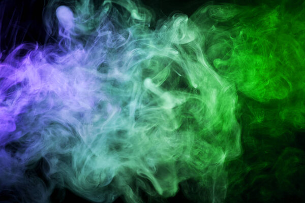 Thick colorful blue and green smoke on a black isolated background. Background from the smoke of vap