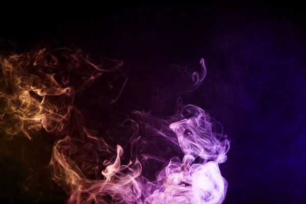 Dense multicolored smoke of orange, pink and blue colors on a black isolated background. Background of smoke vap