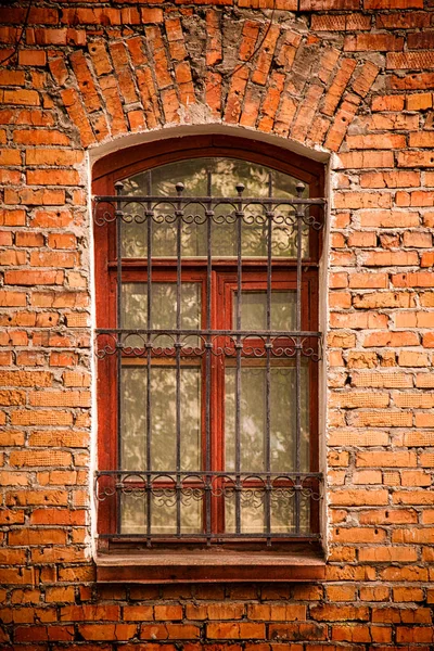 Eski bir kırmızı tuğla ev içinde bölünmüş ızgaraları ile eski bir ahşap pencere Close-up