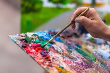 Yakın çekim bir sanatçı bir tuval üzerine yağlıboya etkinlikler ile bir yaz set of bir peyzaj boyar.