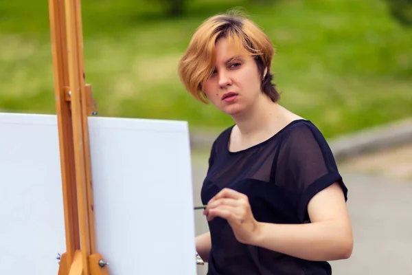 Młoda Blondynka Artystki Czarny Shirt Dżinsy Farby Płótnie Sztalugą Farbami — Zdjęcie stockowe