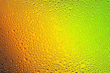 İn yakın bir su damlaları ile kaplı bir sarı, turuncu, yeşil ve kahverengi degrade arka plan üzerinde damla su - yoğunlaşma.