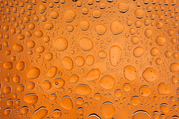 Close Uma Água Cai Sobre Fundo Laranja Coberto Com Gotas — Fotografia de Stock