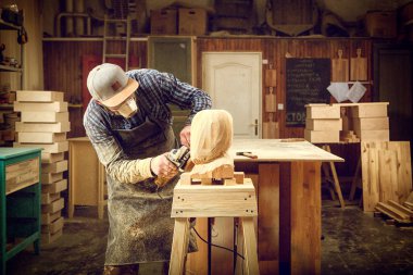 İş elbiseleri ve küçük buiness sahibi doğrama atölyesinde çalışan deneyimli marangoz işler kurulu bir açı ile masaya değirmeni bir çekiç ve birçok araç olduğunu 