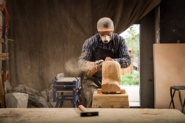İş elbiseleri ve ahşap atölyesinde, işlemler çalışma küçük buiness sahibi marangoz masada bir açı değirmeni ile tahta bir çekiç ve birçok araç olduğunu 