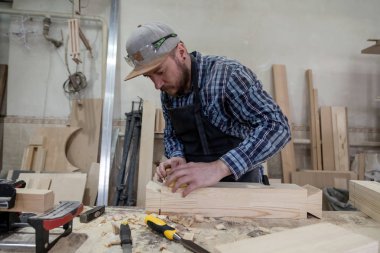 Esmer bir adam bir sakal ve koruyucu Yeşil gözlük ahşap ürün atölye bir keski ile tedavi