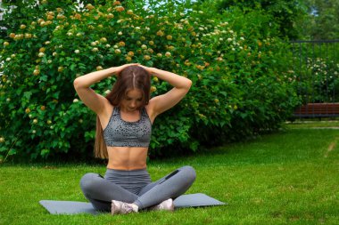 Güzel ince kadın sporcumuz egzersiz, bir yoga mat parkta yeşil çim üzerinde bir yaz gününde Press bir yapar yapmak