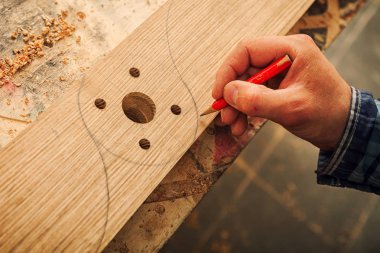 Yakından bakınca tahta bir tahta ölçer ve dilimler için gerekli noktaları kalemle işaretler.