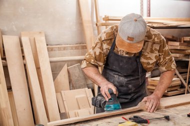 Bir rasgele yörünge sander atölye ile bir genç adam Oluşturucusu marangoz eşittir cilalar ahşap Yönetim Kurulu kapat