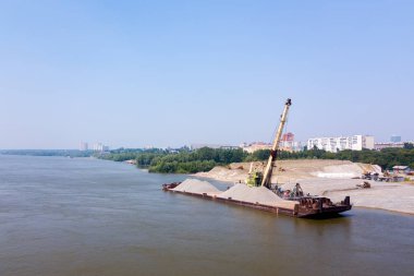 Havadan görünümü: mavna kargo ve inşaat ile vinç arka planda Nehri'ndeki modern bir şehir ve bir park. Kargo gemisi Nehri üzerinde.