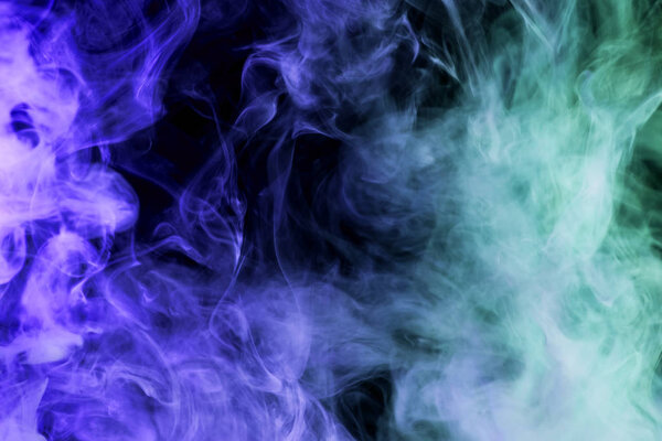 Dense multicolored blue smoke on a black isolated background. Background of smoke vap