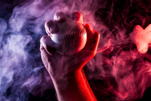 Colorful baseball ball in multi-colored red smoke from a vape on a black  isolated background