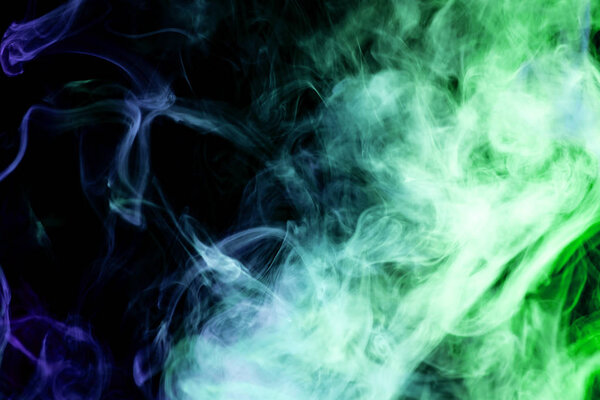Thick colorful smoke of blue and green on a black isolated background. Background from the smoke of vap