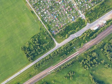 Helikopter dron vurdu. Yukarıdan küçük bir köy, motor yol, yeşil orman ve büyük bir alan üzerinde bir sıcak, güneşli yaz günü görüntüleyin