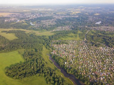 Üstten görünüm küçük evleri,, yeşil orman ve bir sıcak güneşli yaz günü büyük bir alanda büyük bir köy. Helikopter dron vurdu.