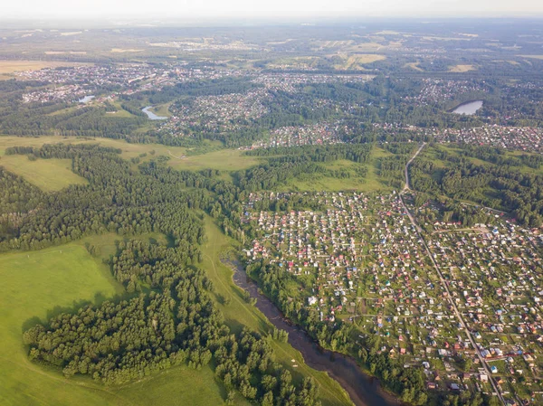 Üstten görünüm küçük evleri,, yeşil orman ve bir sıcak güneşli yaz günü büyük bir alanda büyük bir köy. Helikopter dron vurdu.