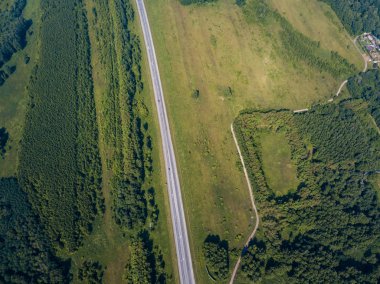 Üstten görünüm yol, yeşil orman ve bir sıcak güneşli yaz günü büyük bir alanda. Helikopter dron vurdu.
