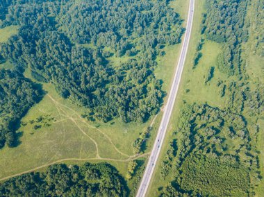 Üstten görünüm yol, yeşil orman ve bir sıcak güneşli yaz günü büyük bir alanda. Helikopter dron vurdu.