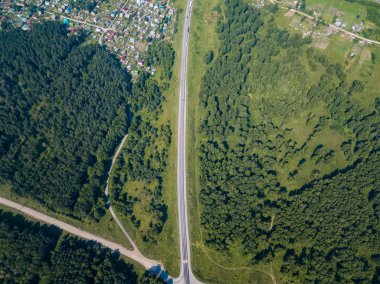 Üstten görünüm yol, yeşil orman ve bir sıcak güneşli yaz günü büyük bir alanda. Helikopter dron vurdu.
