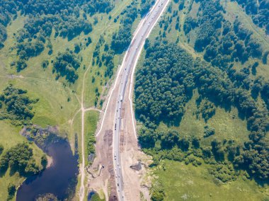 Üstten görünüm yol, yeşil orman ve bir sıcak güneşli yaz günü büyük bir alanda. Helikopter dron vurdu.