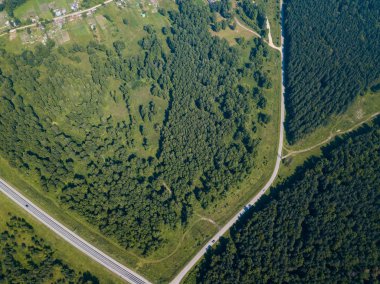 Üstten görünüm yol, yeşil orman ve bir sıcak güneşli yaz günü büyük bir alanda. Helikopter dron vurdu.