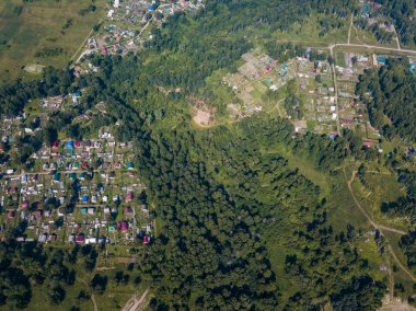 Helikopter dron vurdu. Yukarıdan küçük bir köy, motor yol, yeşil orman ve büyük bir alan üzerinde bir sıcak, güneşli yaz günü görüntüleyin