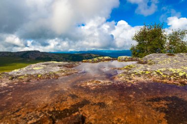Büyük bir taş bir close-up parlak mavi gökyüzü yansıtan su havuzları ile. Altay ve sıcak yaz gününde mavi gökyüzü yüksek dağları arka plan üzerinde