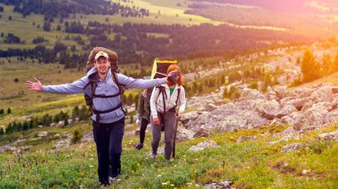 Yaşam tarzı ve yaşam kavramı arka profili seyahat. Yürüyüş kadınlar ve erkekler trekking, zevk sırt çantası ile yeşil bir alana, dağlar içinde belgili tanımlık geçmiş dağlara gidin. Güneş parlıyor, sıcak yaz gününde mavi gökyüzü.