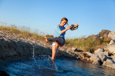Bir neşeli esmer kadın gülümsüyor, plaj boyunca dalgalar başladı, devamlı spreyler ve parlak güneşin bir yaz gününde sahiptir. Deniz ve canlı stil yaz tatilleri kavramı