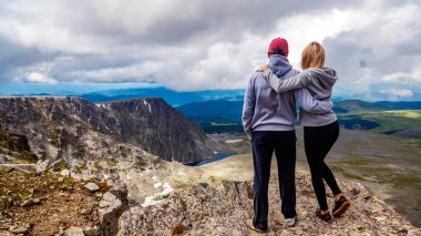 Atmosferik an için dağlarda aşık. Kadın ve montaj üstünde duran ve güzel bir manzaraya bakarak adam hiking. Yaşam tarzı ve yaşam kavramı arka profili seyahat