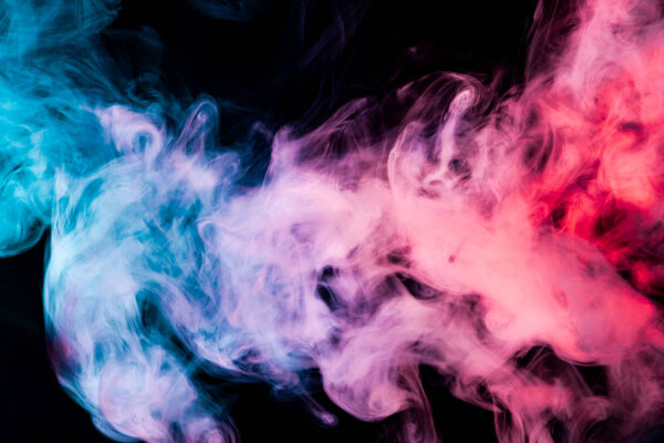 Thick colorful blue, pink and purple smoke on a black isolated background. Background from the smoke of vap