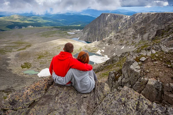 Atmospheric moment for lovers in the mountains. Hiking woman and man standing on the top of the mounting and looking at a beautiful landscape. Travel Lifestyle and survival concept rear view