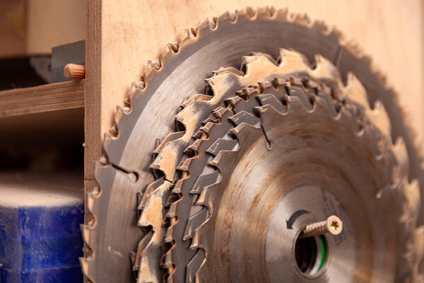 Close up of a many metal circular saw blades different sizes on a wooden background in workshop