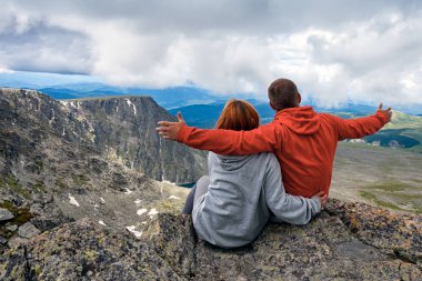 Karlı dağlar gökyüzü karşı genç mutlu çift. Atmosferik an dağlarda sevenler için. 
