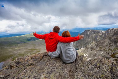Karlı dağlar gökyüzü karşı genç mutlu çift. Atmosferik an dağlarda sevenler için. 