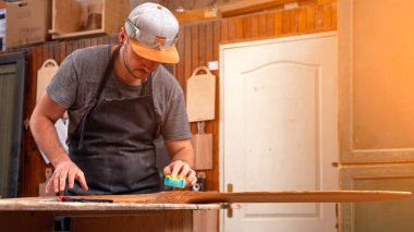 İş elbiseleri ve doğrama atölyesinde çalışan küçük buiness sahibi parlatma ve claening çocuk helikopter bıçakları atölye worktable için zımpara kullanarak deneyimli marangoz  