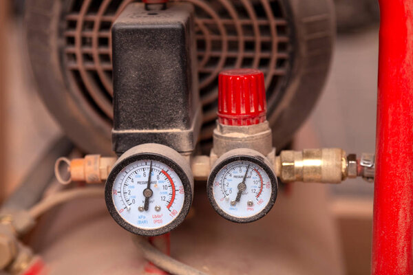 Крупный план редуктора и датчика давления на современном оборудовании на заводе в фоновом промышленном цехе, вид сбоку
