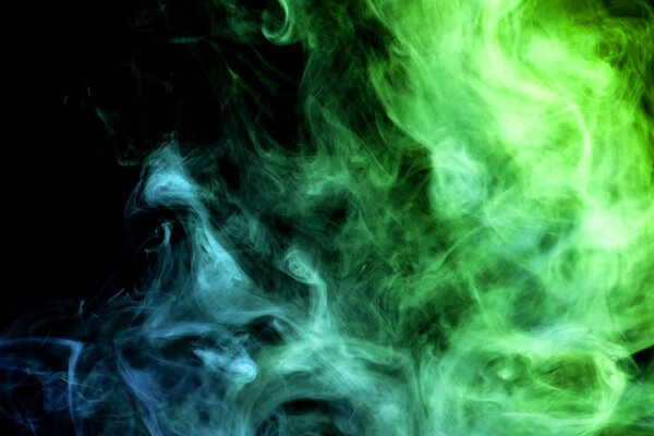 Dense green and blue smoke on a black isolated background. Background of smoke vap
