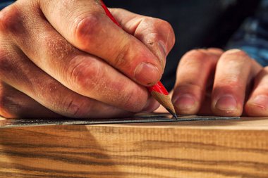 Yakından bakınca tahta bir tahta ölçer ve dilimler için gerekli noktaları kalemle işaretler.