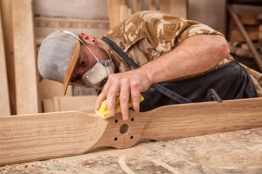 İş elbiseleri ve doğrama atölyesinde çalışan küçük işletme sahibi çocuk helikopter bıçakları atölye worktable parlatma için zımpara kullanarak deneyimli marangoz  