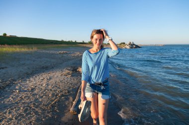 Bir neşeli esmer kadın gülümsüyor, plaj boyunca dalgalar başladı, karpuz yemek ve parlak güneşin bir yaz gününde sahiptir. Deniz ve canlı stil yaz tatilleri kavramı