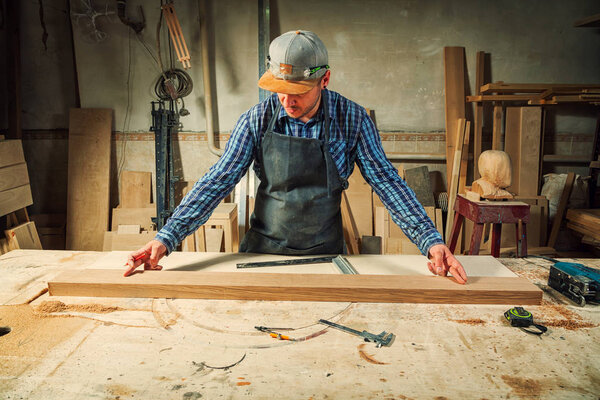 Close-up The man measures a wooden board with a ruler and marks with pencil the necessary points for slices