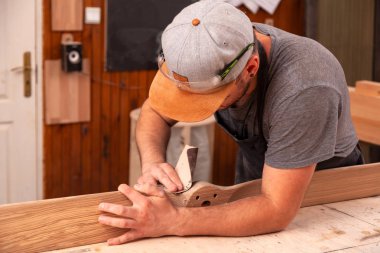  Bir adam marangoz bir kap içinde gözlük ve bir T-shirt zımpara ahşap arka plan atölye birçok araç 