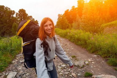 Sırt çantası ile yürüyüş kadın neşeyle gülümsüyor, dağlarda yürüyüş sahiptir. Orman, üstüne hipster seyahat etmek görünüm şaşırtıcı. Yolculuk tutkusu eğlenceli ve concep seyahat