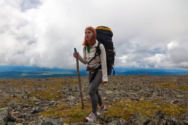 Atmosferik an dağlarda. Sırt çantası gezgin dağlar üstüne kadınla hiking. Şık kadın Hiking, arka planda bir yeşil orman, alan ve yüksek dağ