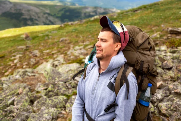 Travel Lifestyle and survival concept rear view. Hiking men with backpack  are very tired , enjoying the trekking, in the background  mountains. Wanderlust and travel concept