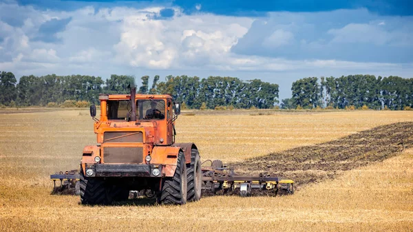 Ein Oranger Moderner Traktor Pflügt Die Erde — Stockfoto