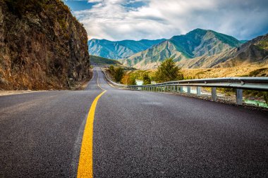 Asfalt yol. Güzel dağ yolu ile mükemmel bir asfalt ile manzara. Yüksek kayalar, yaz aylarında gün batımında gökyüzü şaşırtıcı. Panoramik. Arka plan seyahat. Dağların üst