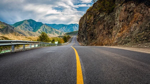 Asfalt yol. Güzel dağ yolu ile mükemmel bir asfalt ile manzara. Yüksek kayalar, yaz aylarında gün batımında gökyüzü şaşırtıcı. Panoramik. Arka plan seyahat. Dağların üst