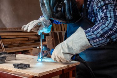 Güçlü adam Kaynakçı çalışmalarında çalışkan elbise ve bir kaynak makine metal kaynak